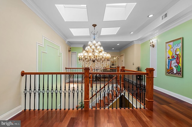 hall featuring an inviting chandelier, visible vents, crown molding, and an upstairs landing