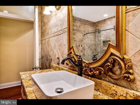 bathroom featuring tiled shower, vanity, and hardwood / wood-style flooring