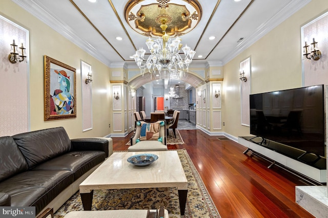 living area featuring arched walkways, crown molding, wood finished floors, baseboards, and an inviting chandelier