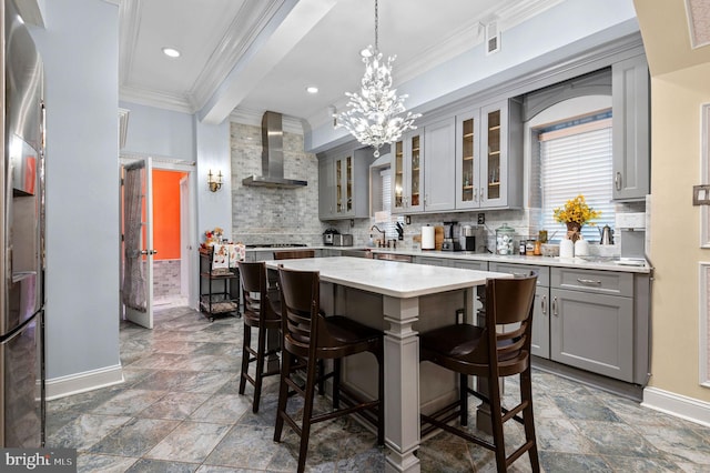 kitchen with glass insert cabinets, gray cabinets, a kitchen island, and wall chimney exhaust hood