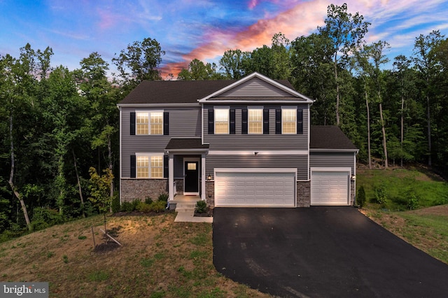 traditional home with a garage, stone siding, and driveway