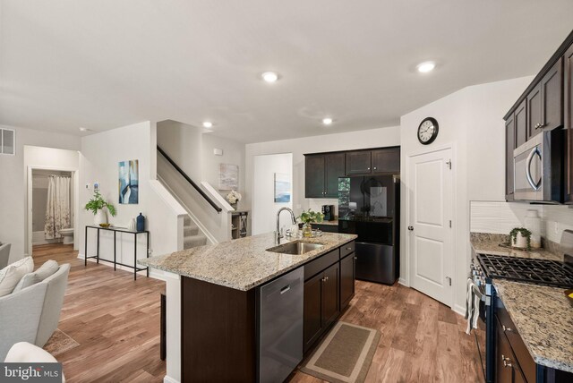 kitchen featuring light wood finished floors, appliances with stainless steel finishes, an island with sink, and a sink