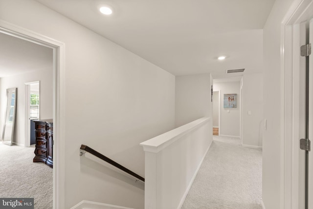 corridor featuring carpet, baseboards, visible vents, and an upstairs landing