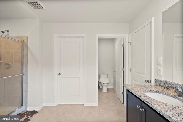 bathroom featuring vanity, toilet, an enclosed shower, and tile patterned flooring