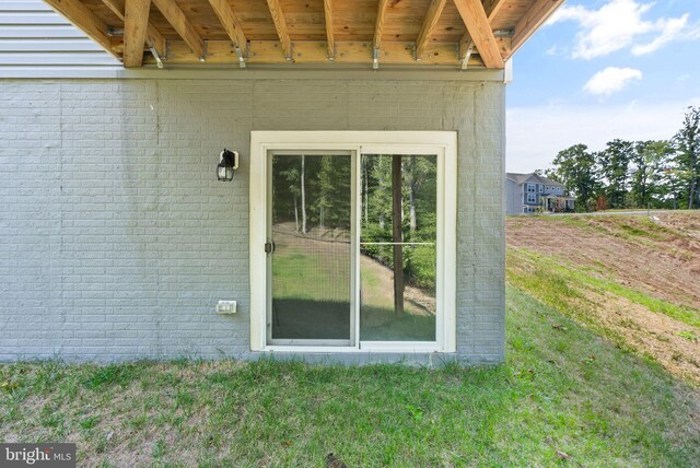 view of exterior entry featuring a lawn