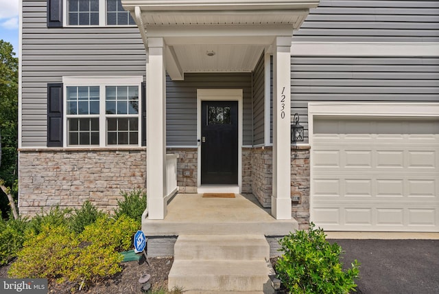 view of exterior entry featuring a garage and stone siding