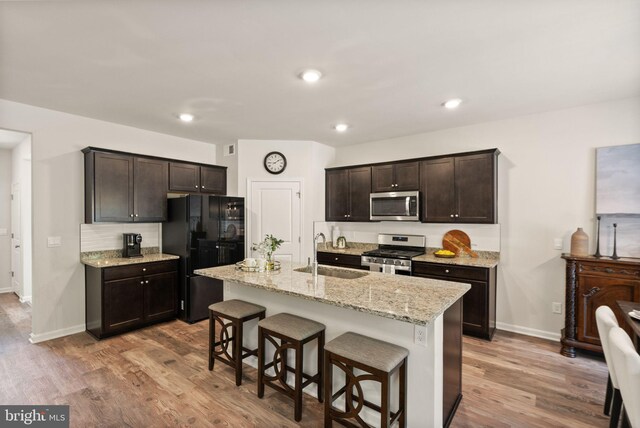 kitchen featuring appliances with stainless steel finishes, light hardwood / wood-style floors, sink, a kitchen breakfast bar, and a kitchen island with sink