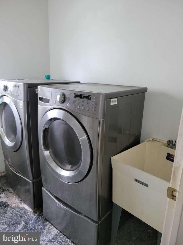 clothes washing area featuring washing machine and dryer and sink