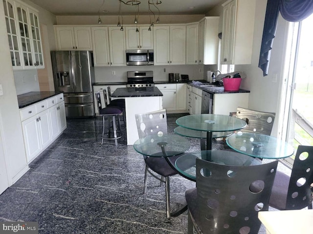 kitchen featuring appliances with stainless steel finishes, a breakfast bar, sink, white cabinets, and a kitchen island