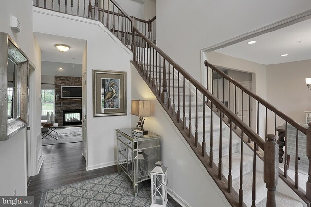 stairway with hardwood / wood-style flooring and a stone fireplace