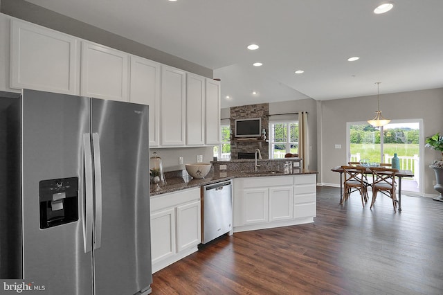 kitchen featuring sink, a stone fireplace, dark hardwood / wood-style flooring, white cabinetry, and stainless steel appliances