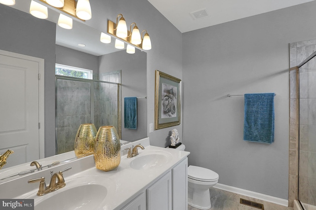 bathroom with wood-type flooring, toilet, dual bowl vanity, and an enclosed shower