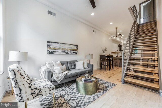 living room with a towering ceiling, light hardwood / wood-style flooring, and a chandelier