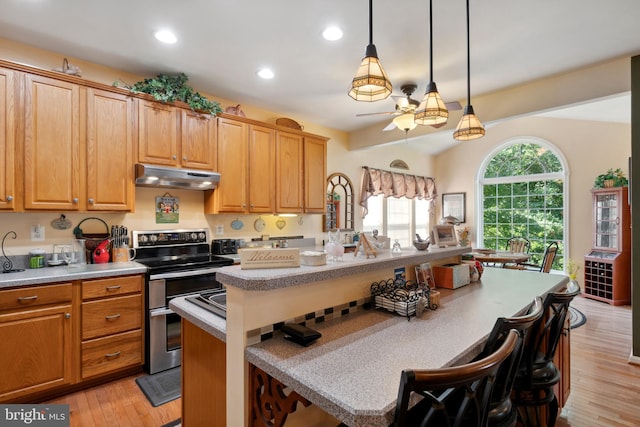 kitchen featuring decorative light fixtures, a kitchen bar, light wood-type flooring, range with electric stovetop, and a center island