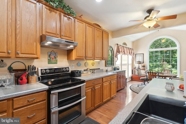 kitchen with light hardwood / wood-style floors, range with two ovens, ceiling fan, and lofted ceiling