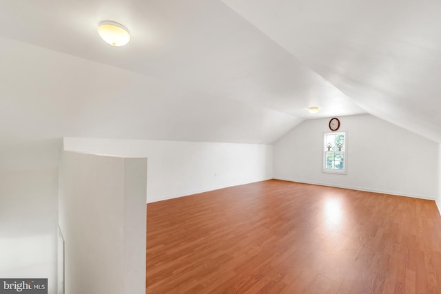 additional living space with hardwood / wood-style flooring and vaulted ceiling