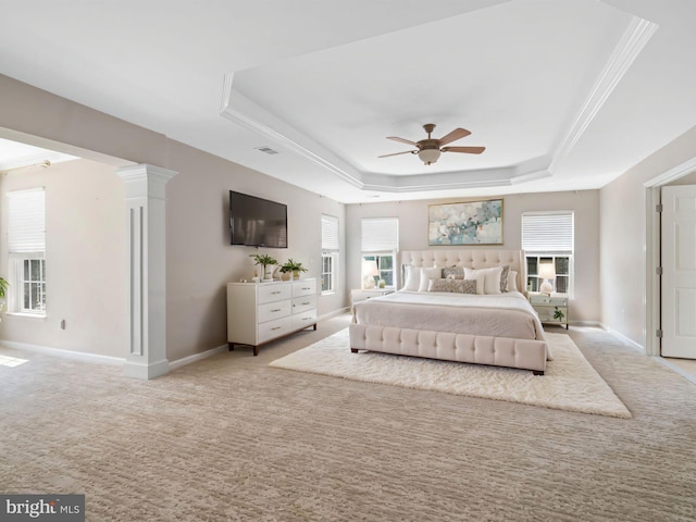 bedroom with ceiling fan, light colored carpet, a tray ceiling, ornate columns, and ornamental molding