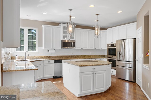 kitchen featuring sink, appliances with stainless steel finishes, light stone counters, light hardwood / wood-style floors, and white cabinetry