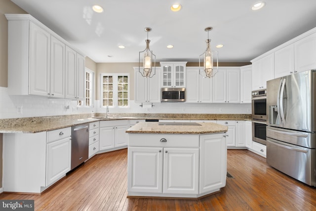 kitchen featuring white cabinets, wood-type flooring, a center island, and stainless steel appliances