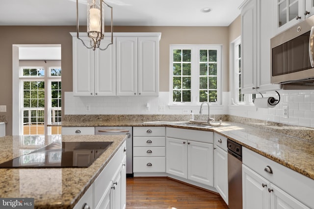 kitchen with stainless steel appliances, decorative backsplash, light stone counters, white cabinets, and wood-type flooring