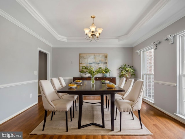 dining room featuring hardwood / wood-style flooring, a raised ceiling, and crown molding