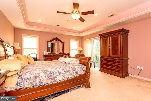 bedroom featuring light carpet, multiple windows, and a raised ceiling