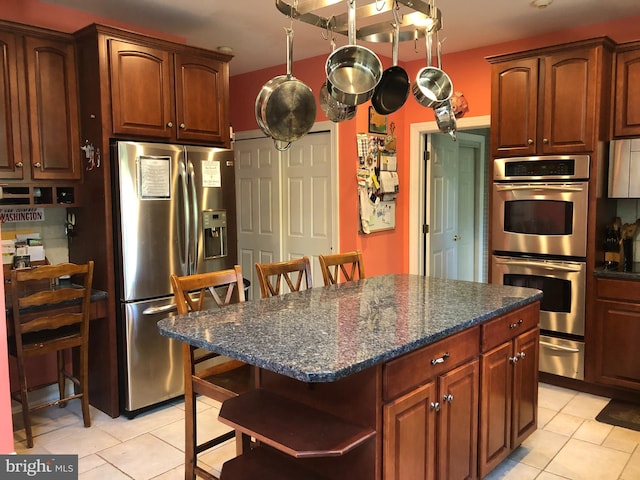 kitchen featuring light tile patterned floors, a center island, stainless steel appliances, open shelves, and a warming drawer