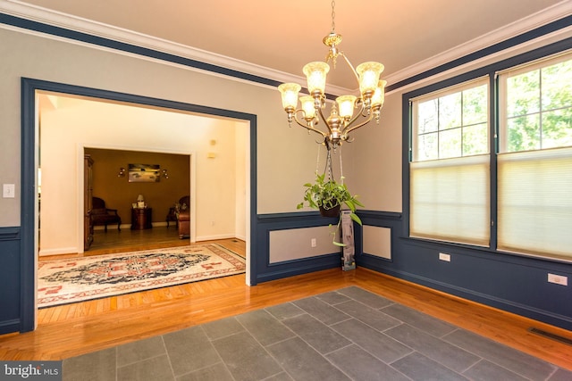 interior space featuring visible vents, a wainscoted wall, ornamental molding, wood finished floors, and an inviting chandelier