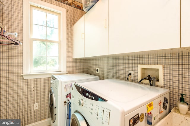 laundry room featuring cabinets, independent washer and dryer, and tile walls