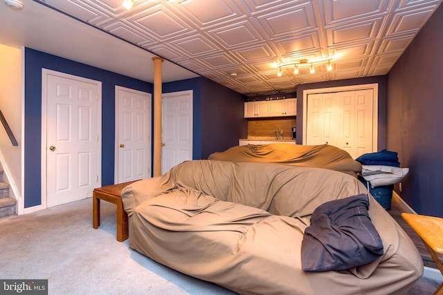 bedroom featuring light carpet, an ornate ceiling, baseboards, and a closet