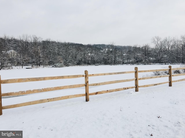 snowy yard featuring fence and a wooded view