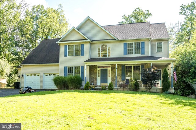 view of front of house featuring a garage, a front yard, and a porch