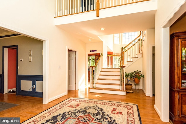 entrance foyer with wood-type flooring and a towering ceiling