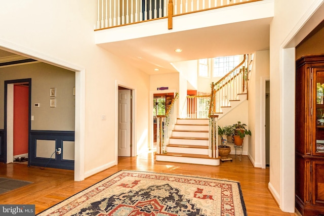 entryway featuring baseboards, stairs, a high ceiling, and wood finished floors