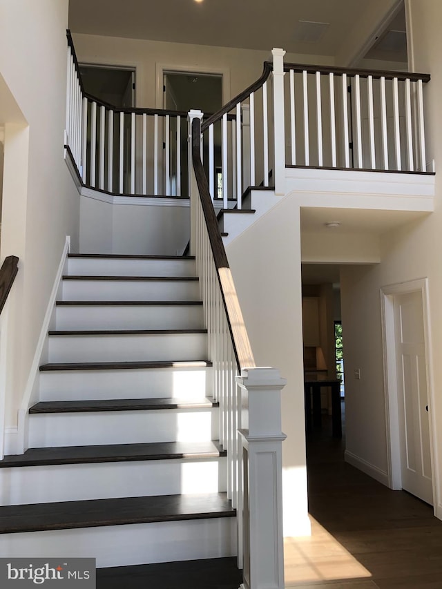 stairs featuring hardwood / wood-style flooring and a towering ceiling