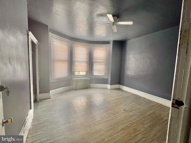 spare room featuring hardwood / wood-style floors, ceiling fan, and radiator