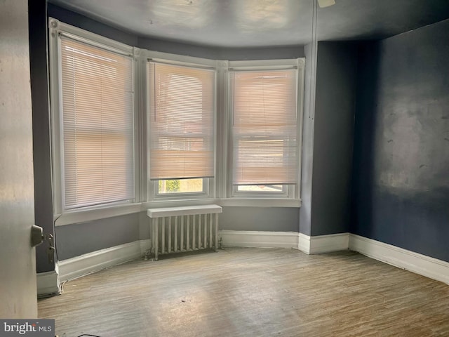 spare room with radiator heating unit and wood-type flooring