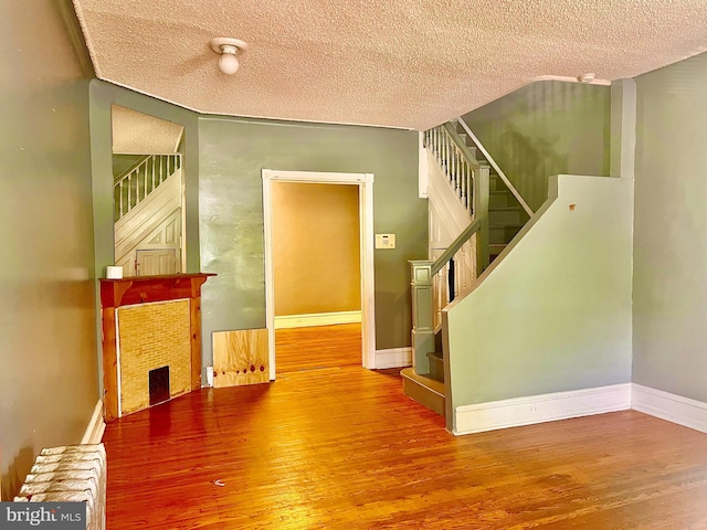 stairs with a textured ceiling, a fireplace, and hardwood / wood-style flooring