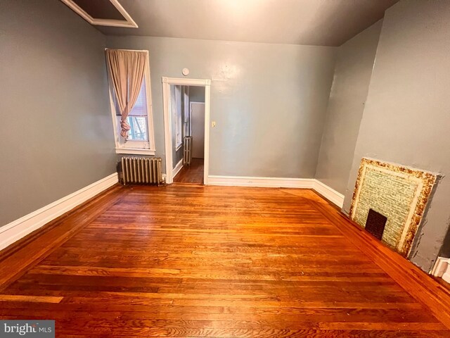 unfurnished room with radiator heating unit and dark hardwood / wood-style flooring