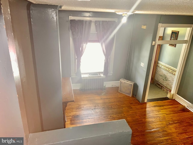 bonus room featuring radiator heating unit, dark wood-type flooring, and a textured ceiling