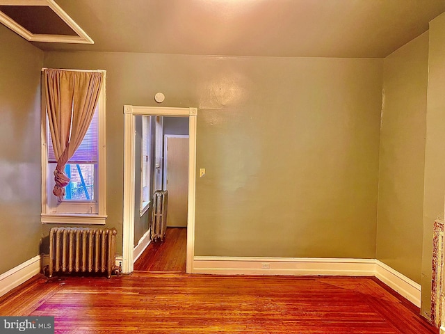 empty room with hardwood / wood-style floors and radiator heating unit