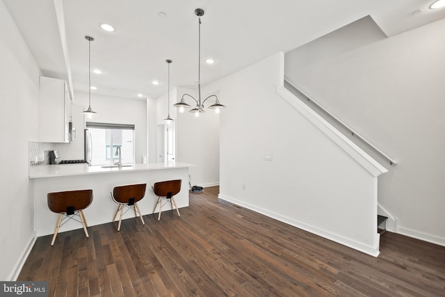 kitchen with hardwood / wood-style floors, a kitchen bar, kitchen peninsula, and white cabinetry