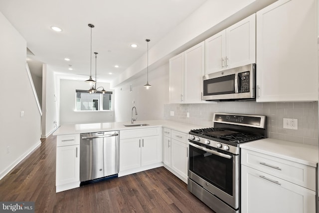 kitchen with decorative backsplash, dark wood-type flooring, hanging light fixtures, sink, and stainless steel appliances