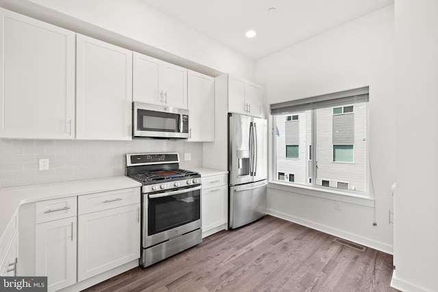 kitchen featuring tasteful backsplash, white cabinetry, appliances with stainless steel finishes, and light hardwood / wood-style floors