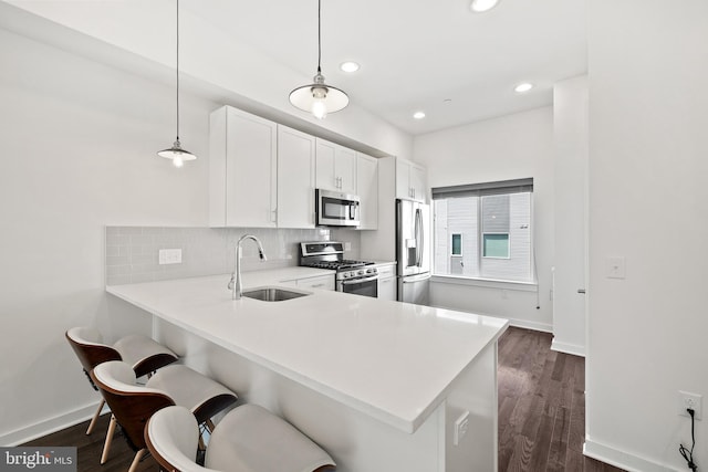 kitchen with backsplash, dark hardwood / wood-style floors, hanging light fixtures, sink, and stainless steel appliances