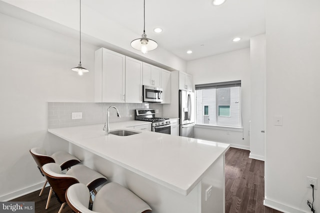 kitchen featuring hanging light fixtures, appliances with stainless steel finishes, a peninsula, and light countertops