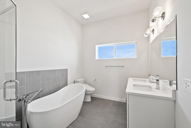 bathroom featuring a bathing tub, toilet, dual vanity, and tile patterned floors