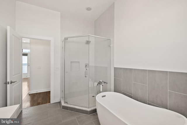 bathroom featuring tile walls, separate shower and tub, and wood-type flooring