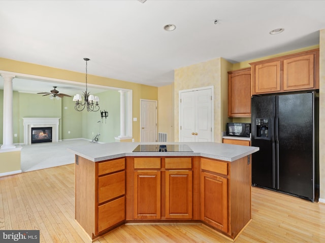 kitchen with black appliances, ceiling fan with notable chandelier, a center island, and ornate columns