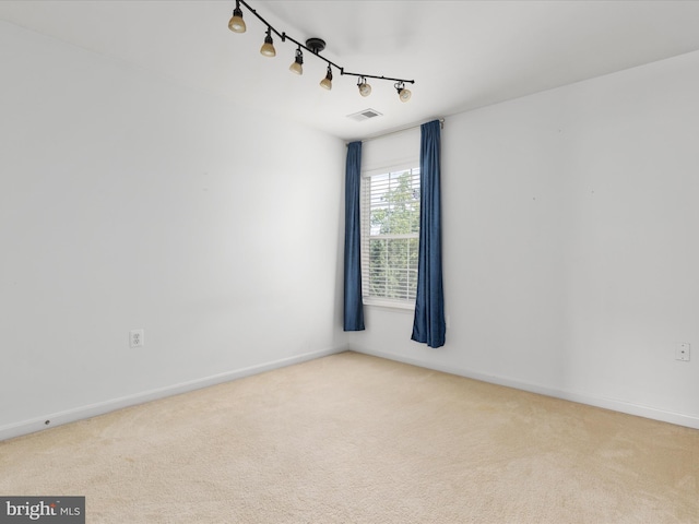 spare room featuring light carpet and track lighting